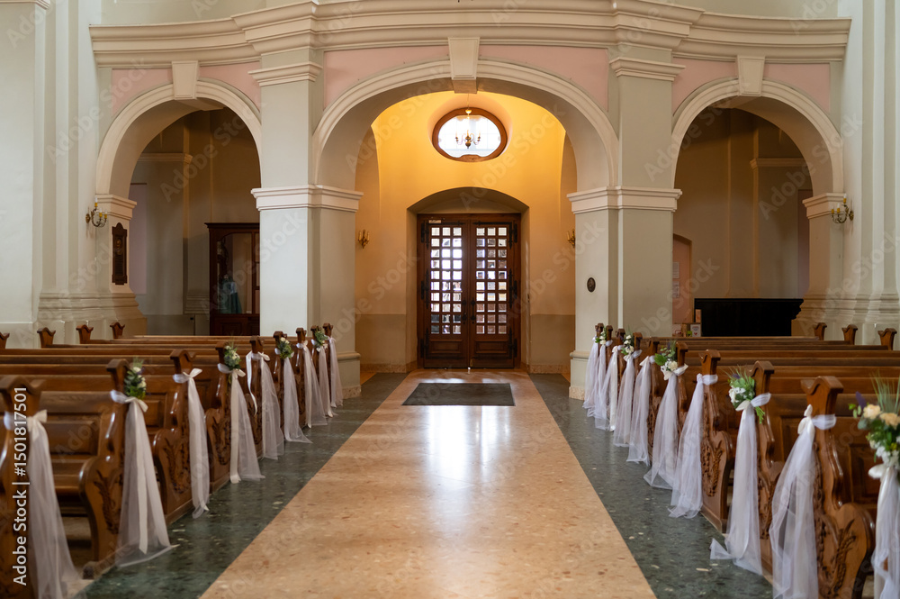 Fototapeta premium A large church with a long aisle of pews and a large altar. The pews are empty and the altar is covered in flowers