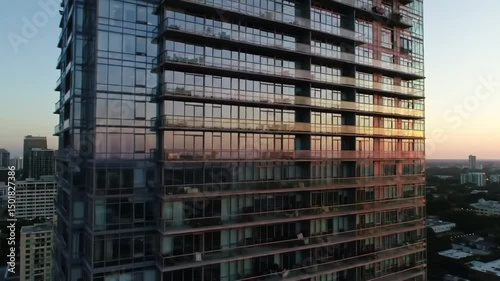 Modern Glass Skyscraper With Balconies Reflecting Sunrise In City