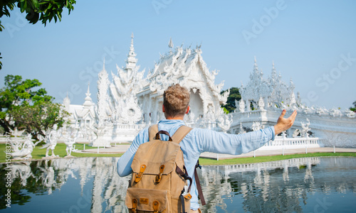 Caucasian male tourist with backpack exploring white temple wat rong khun Chiang Rai photo