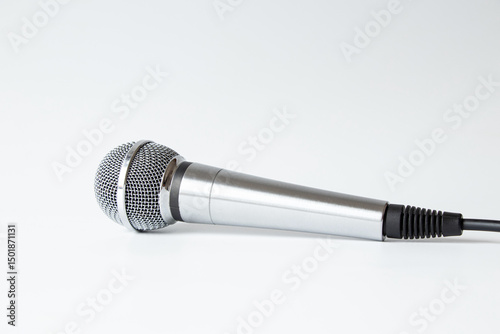Professional silver microphone with cable on white background, studio equipment