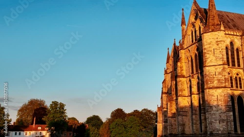 Intricate lancet windows and ribbed vaults adorn the facade of Salisbury Cathedral rising above the tranquil cathedral close, Salisbury, Wiltshire, England, UK
