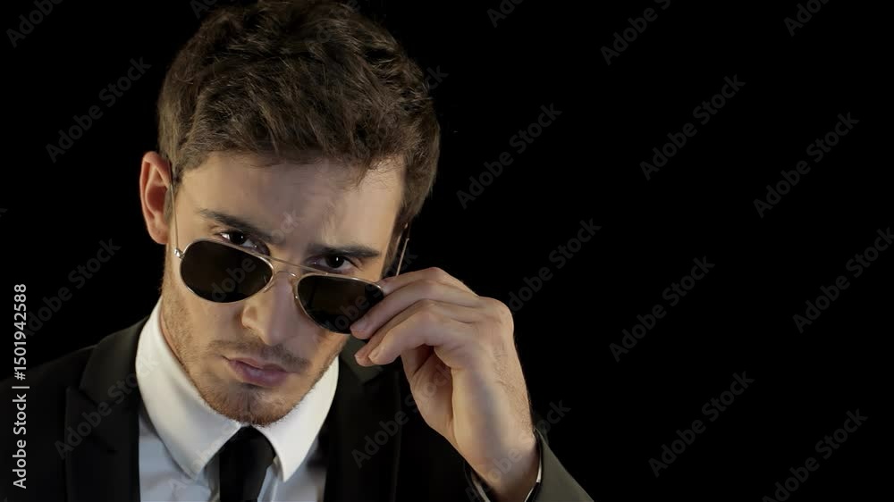 Confident man peering over aviator sunglasses like a suave special agent Confident man peering over aviator sunglasses like a suave special agent
