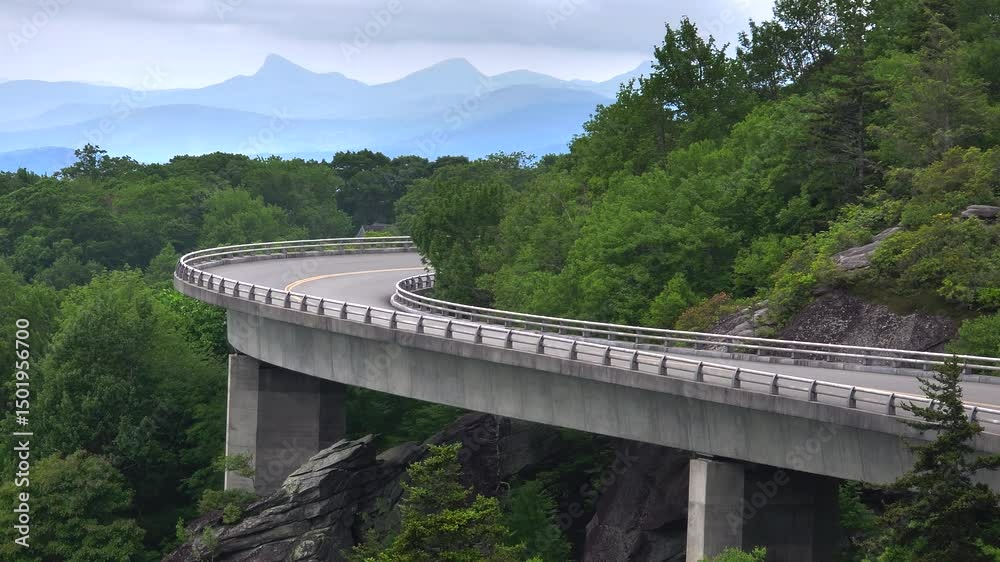 Winding mountain road in summer woods. Linn Cove Viaduct in Appalachian mountains in North Carolina with fresh green forest trees in summertime season. Beauty of USA nature Winding mountain road in summer woods. Linn Cove Viaduct in Appalachian mountains in North Carolina with fresh green forest trees in summertime season. Beauty of USA nature