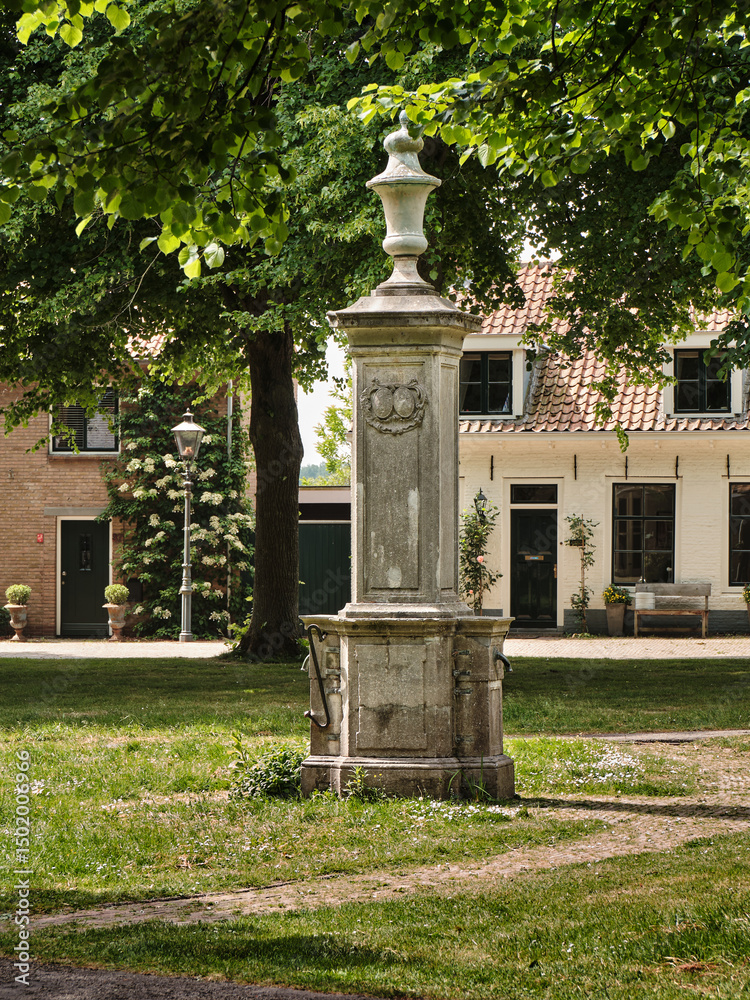 Obraz premium Historic village pump with ornamental column on the green in Nisse, Zeeland