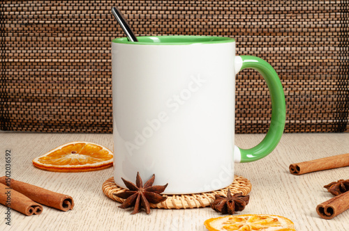 Blank two-tone 11oz mug on on the table. Mug with warm spices like cinnamon, star anise, dried orange. Green handle. Mug mockup