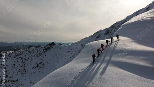 Adventurers climbing snowy mountain ridge in scenic winter landscape