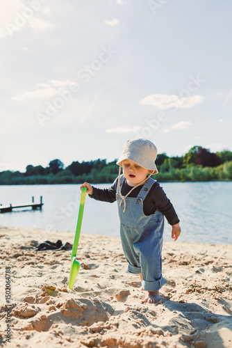 Happy 2 year old little boy playing on sand during summer vacation, wearing hat. Family travel and vacation, outdoor activities on summer beach holiday with children.