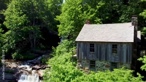 Idyllic Cabin Beside Cascading Waterfall Nestled Within Lush Forest Scenery