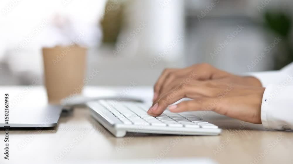Close-up of Hands Typing on a Keyboard at an Office Desk with Coffee Cup Close-up of Hands Typing on a Keyboard at an Office Desk with Coffee Cup