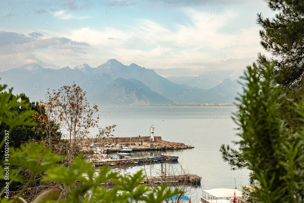 Naklejka premium Serene harbor with distant mountains and lighthouse in calm waters