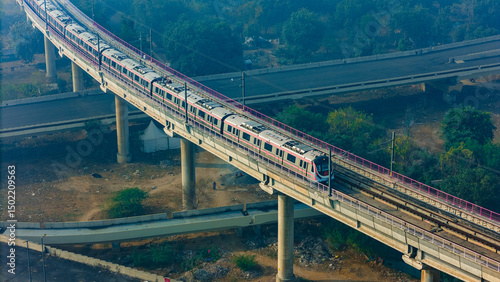 Top down view of The Delhi Metro is running on the tracks towards the Blue Line and Pink Line. Delhi Metro train. Cinematic drone shot of Metro rail in delhi.