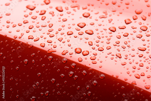 Close-up of red glossy surface with water droplets, showing detail of wet texture and fresh, clean appearance. Ideal for themes of automotive, moisture, and surface texture.
