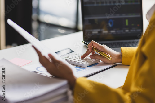 Serious female accountant working with financial documents in office and auditing accounts. Auditor checking financial report documents on desk.