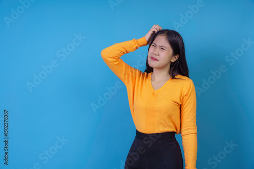 Studio portrait of a young woman scratching her head with a confused and puzzled expression, depicting forgetfulness or uncertainty