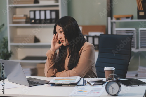 Asian women are stressed while working on laptop, Tired asian businesswoman with headache at office, feeling sick at work, copy space