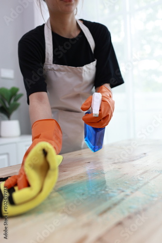 A cheerful young woman confidently cleans her apartment, embracing weekend chores with a smile, showcasing hygiene, responsibility, and domestic life indoors.
