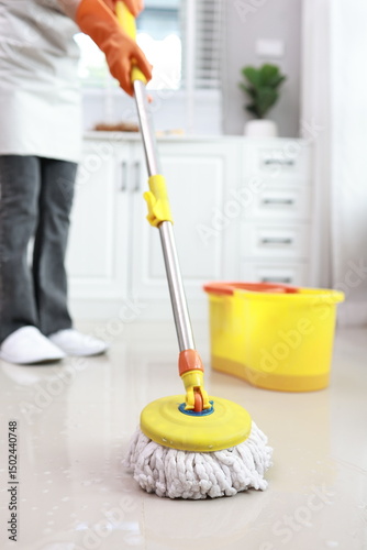 A professional cleaner in uniform works indoors, diligently sanitizing office surfaces. Focused and hygienic, the adult uses spray and cloth to maintain a clean, safe environment.