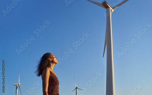 Serene contemplative woman against the sky and wind turbines