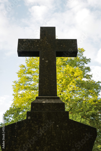 Stone cross cemetery graveyard with garden park trees. Ceremony religios statue faith concept.