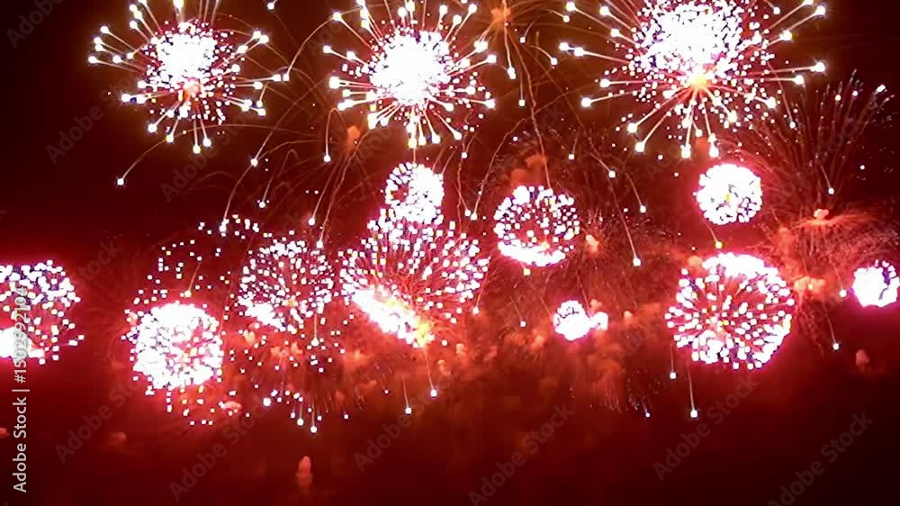 A breathtaking celebration unfolds as dazzling red fireworks burst into life, creating a spectacular light show that captivates the audience under the starry night sky.