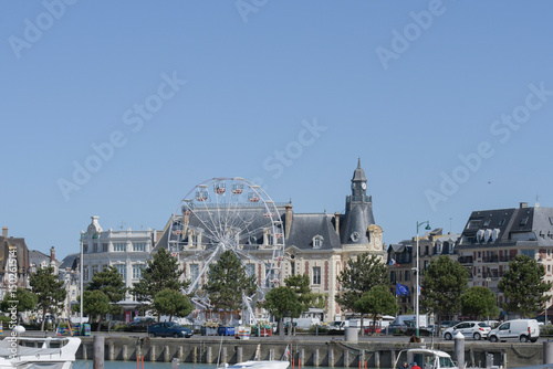 Coastal town features a large Ferris wheel and historical architecture under clear blue sky 2025-04-16 Rouen Normandy-France photo