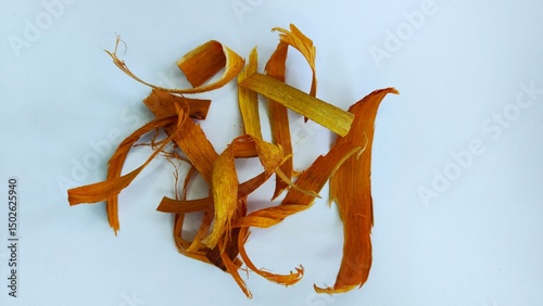 Close up of dry bark chips on a white surface, this is sappanwood, which is commonly used for herbal medicine.