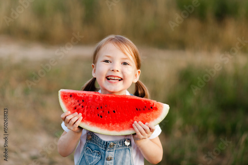 Child enjoying watermelon in summer outdoors