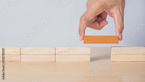Canvas Print Business concept image showing a man connecting two sides using a orange wooden block, representing finding solutions, bridging gaps, and resolving issues