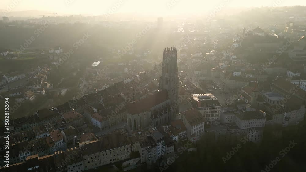 Fribourg, Switzerland: Cinematic aerial drone footage of the sunset over the famous gothic St Nicolas cathedral in Fribourg, or Freiburg in German, famous medieval old town in Switzerland. 