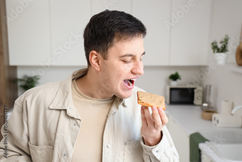 Young man eating toast with...
