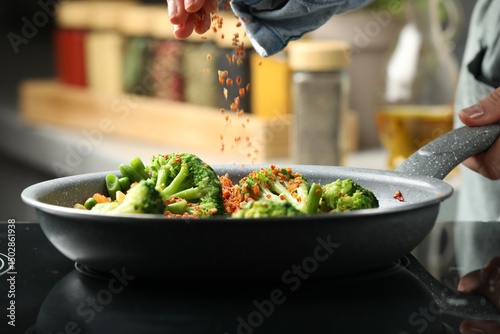 Fototapeta Naklejka Na Ścianę i Meble -  Woman adding spices to dish in kitchen, closeup