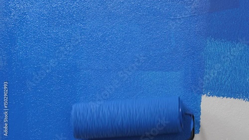 Roller Brush Painting, Worker painting on surface wall Painting apartment, renovating with blue color paint. Leave empty copy space white to write descriptive text beside.