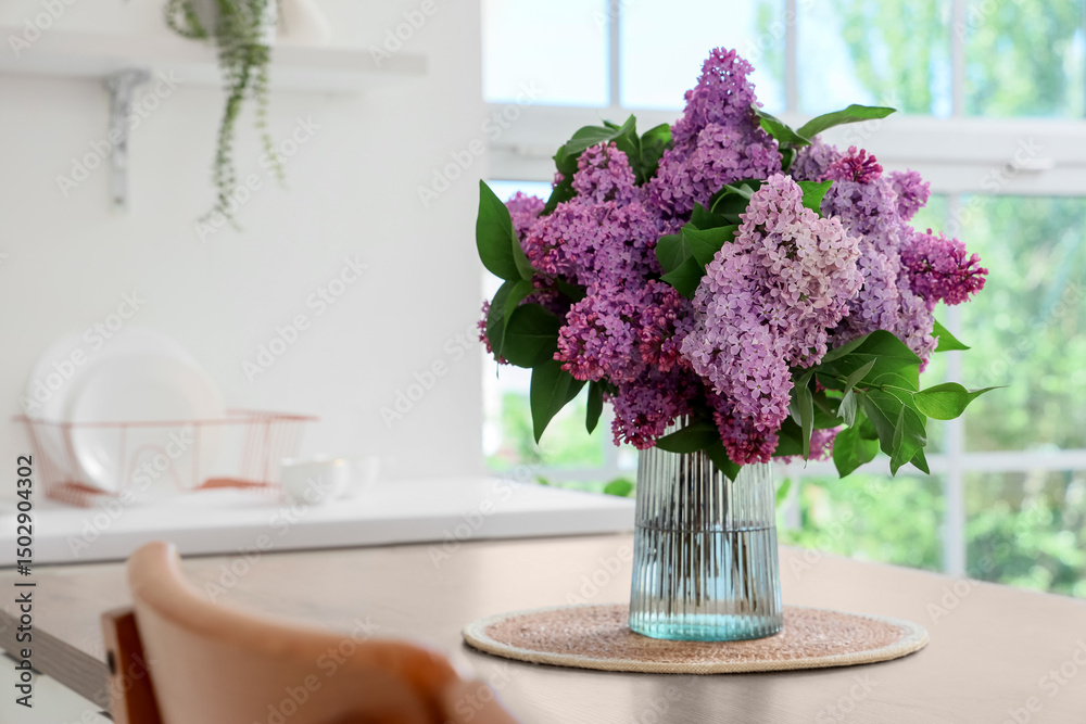 Fototapeta premium Vase with lilac flowers on table in kitchen