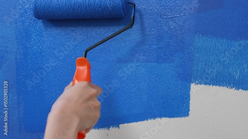 Roller Brush Painting, Worker painting on surface wall Painting apartment, renovating with blue color paint. Leave empty copy space white to write descriptive text beside.
