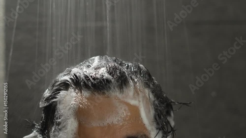 man bathing wash his hair with shampoo in shower. for hygiene. Liquid drops, and foam wash for texture and cleaning routine.