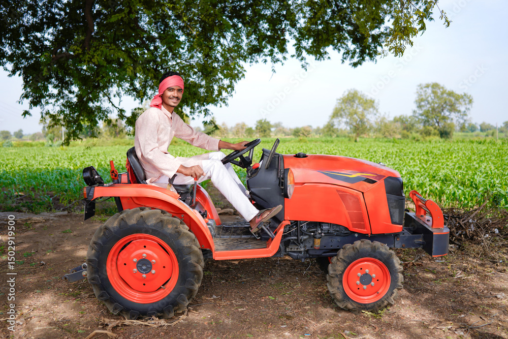 Obraz premium Happy young indian farmer standing with new tractor at agriculture field