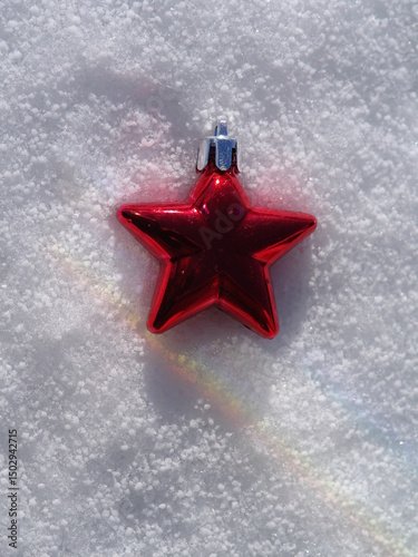 Red star ornament is sitting on top of a snowy surface