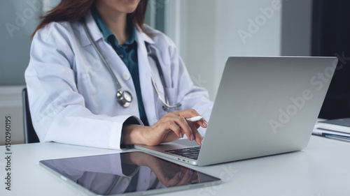 Doctor working in office, using laptop computer to access patient records on an EHR system. Medical student, female doctor using modern technology in practice for medical research, close up