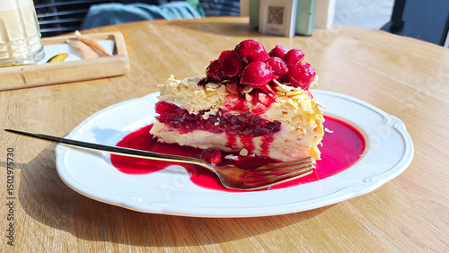 Napoleon pie with cherries and berry sauce on a white plate on a wooden background. Mobile photography photo