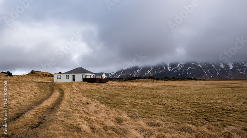 Icelandic landscape in winter. Farmland field, farmhouse, lodge, holiday house, chalet cloudy sky. Iceland Europe