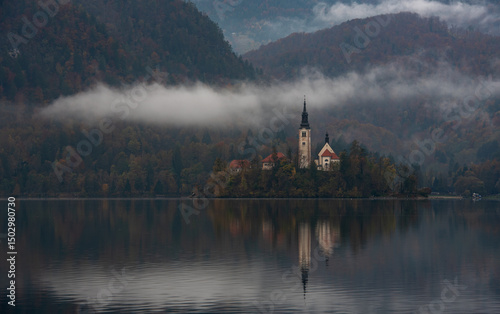 Assumption of mary pilgrimage church on lake bled, surrounded by mountains and colorful autumn foliage, in slovenia