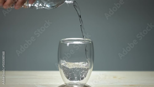 Clear water streaming into a glass against a white background, capturing the simple elegance of this everyday moment.