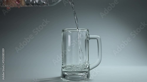 Clear water streaming into a glass against a white background, capturing the simple elegance of this everyday moment.