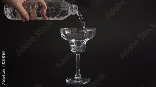 Clear water streaming into a glass against a dark background, capturing the simple elegance of this everyday moment.