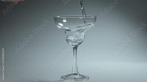 Clear water streaming into a glass against a white background, capturing the simple elegance of this everyday moment.