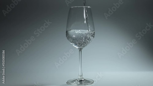 Clear water streaming into a glass against a white background, capturing the simple elegance of this everyday moment.