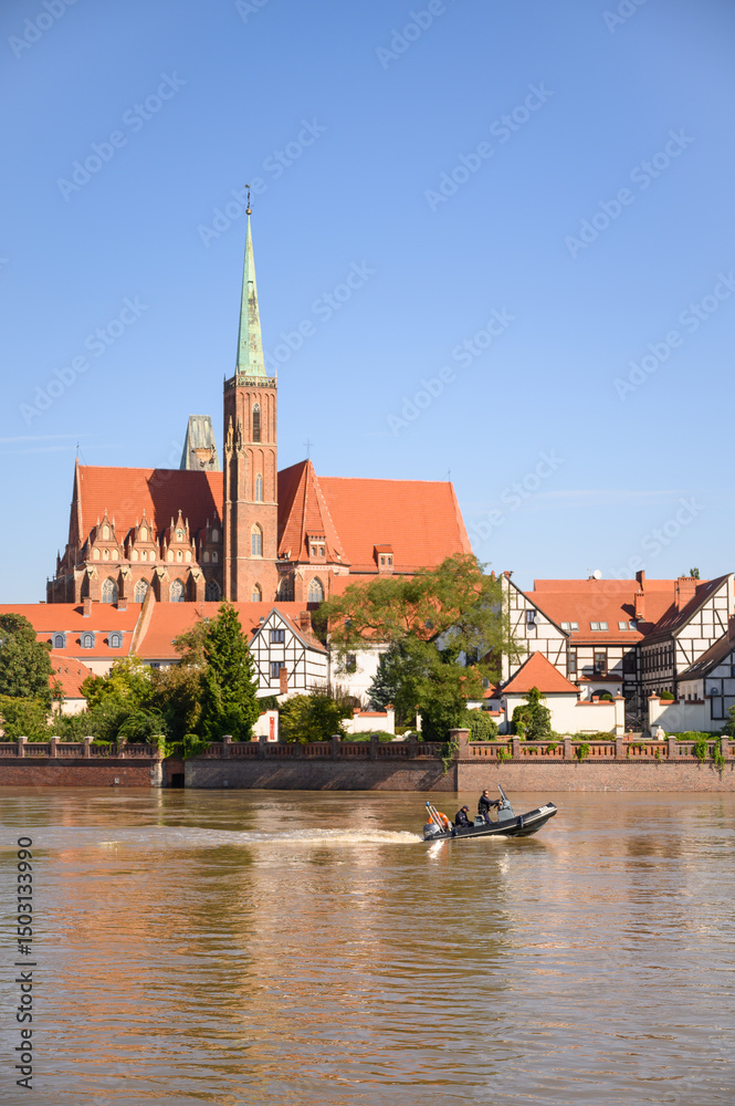 Fototapeta premium Wroclaw Poland 09.21.2025 Emergency services patrol the flooded Odra River during high water levels in the city. The patrol boat is seen near Cathedral on Tumski Island amid flood response operations.
