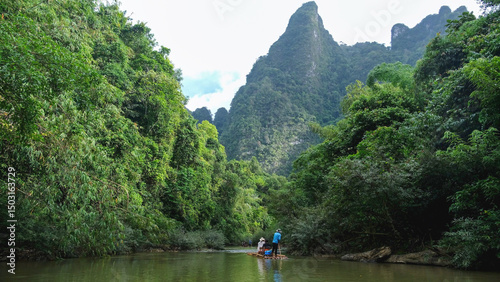 Canvastavla People riding bamboo raft along the river and the greenery rainforest in Khao So