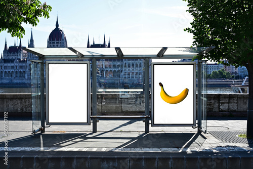 bus shelter at bus stop. transit station. blank white lightbox. empty billboard and ad placeholder. glass structure. urban setting. city skyline and street background. stone sidewalk. base for mockup