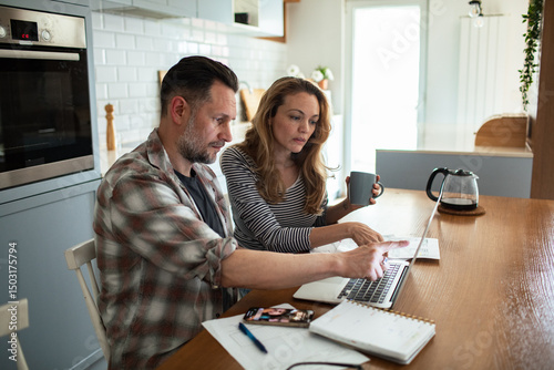 Stressed couple reviewing bills and finances at kitchen table